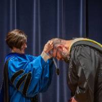 Provost Mili drapes medal around man's neck